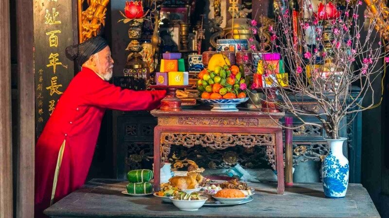 Mâm cỗ cúng giao thừa ngoài trời với hoa quả, gà luộc và bánh chưng