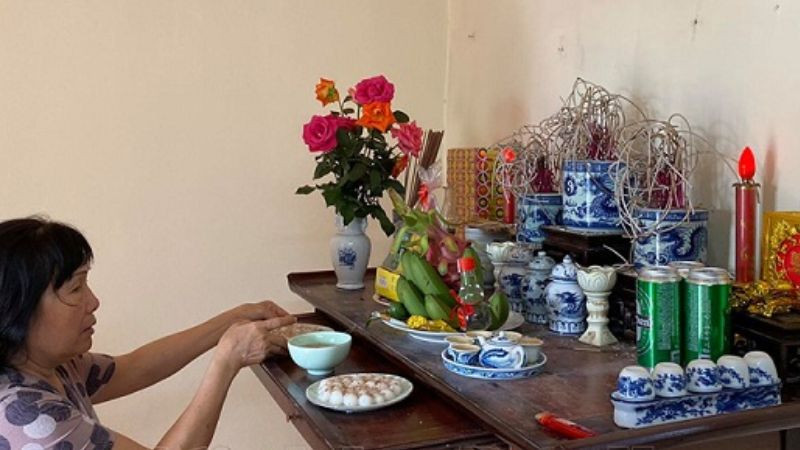 Người phụ nữ chắp tay thành tâm khấn vái trước bàn thờ, thực hành văn khấn 3 3 âm lịch để tưởng nhớ gia tiên.